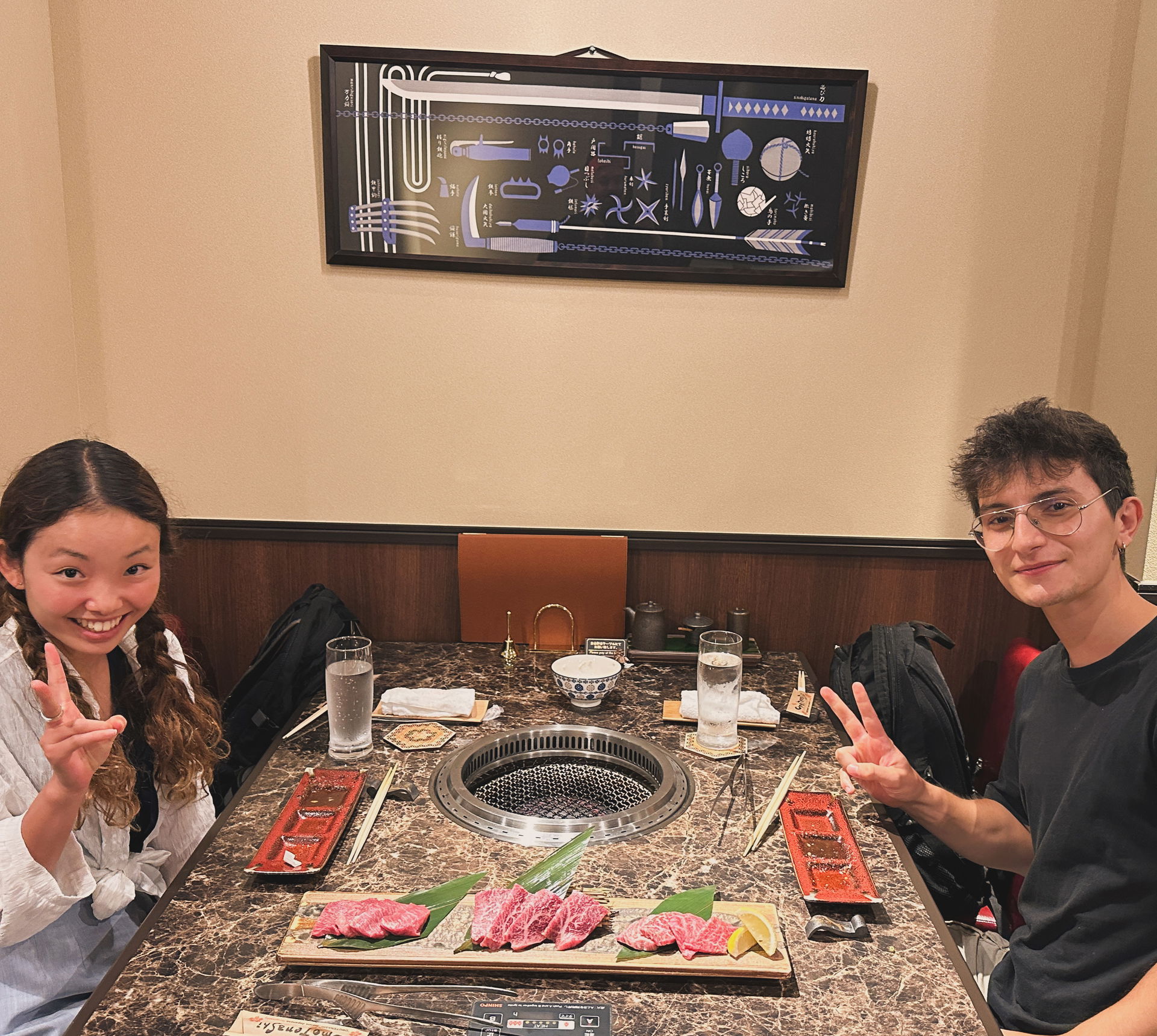 Two guests smiling and making peace signs while grilling meat on this Asakusa walking and food tour.
